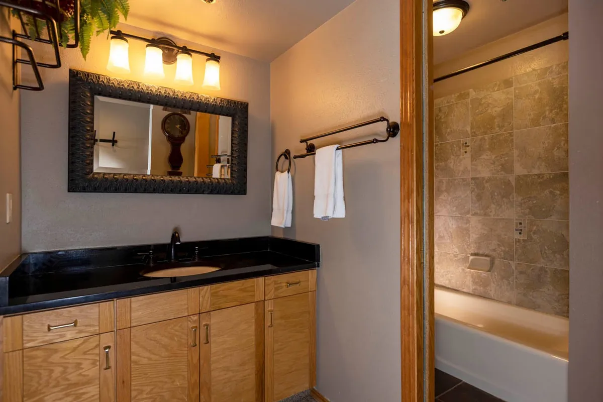 A calm, well-organized ensuite bathroom featuring a modern sink, large mirror, cabinetry for storage, and soft, soothing lighting. The setup suggests comfort, privacy, and a space designed for unwinding and self-care.